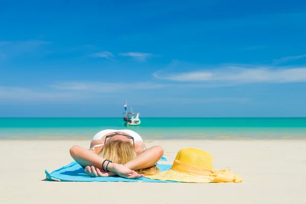 Žena leží na pláži s žlutým kloboukem a ručník — Stock fotografie