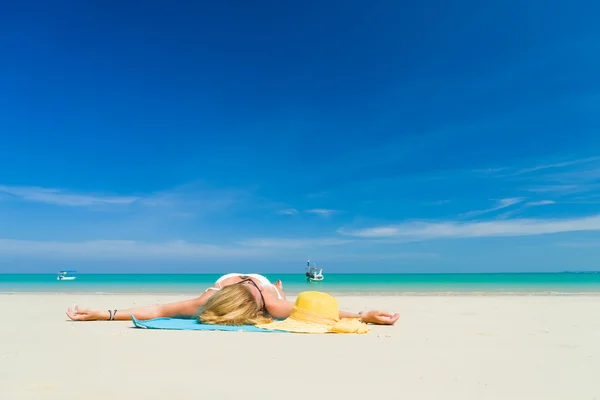 Mujer se encuentra en la playa con sombrero amarillo y toalla —  Fotos de Stock