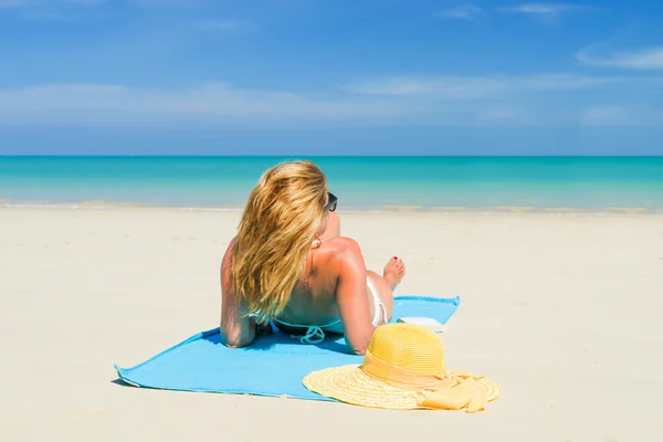 Kobieta leży na plaży z żółtym kapeluszu i ręcznik — Zdjęcie stockowe