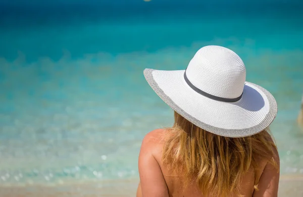 Ung kvinne i hvit bikini ser på vann – stockfoto