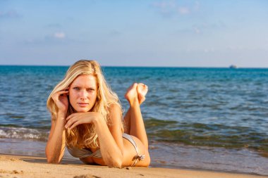 Kumsalda bikinili sarışın kadın.