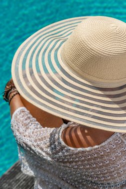 Lüks içinde hasır şapkalı bir kadın. Yüzme havuzunun yanında beş yıldızlı bir spa merkezi.. 