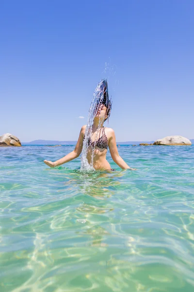 Jeune femme dans la mer éclaboussant l'eau — Photo