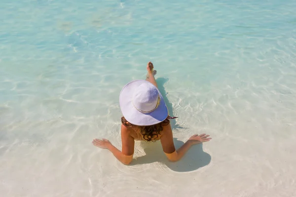 Mulher sentada em uma piscina com um chapéu de sol — Fotografia de Stock