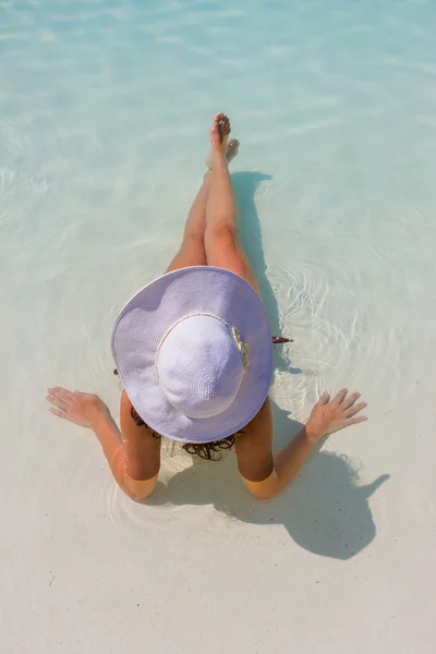 Mulher sentada em uma piscina com um chapéu de sol — Fotografia de Stock