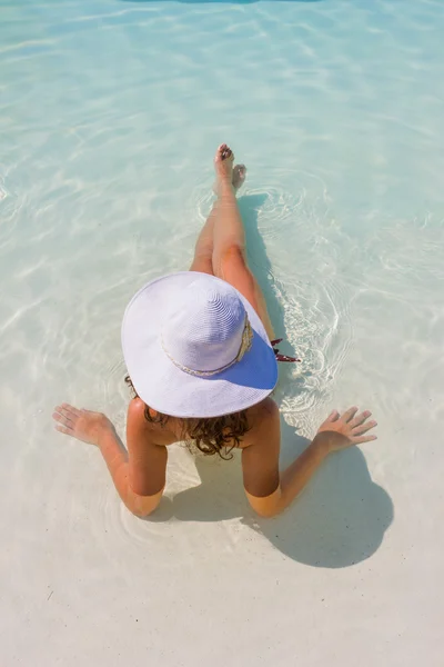 Kvinna sitter i en swimmingpool i en solhatt — Stockfoto