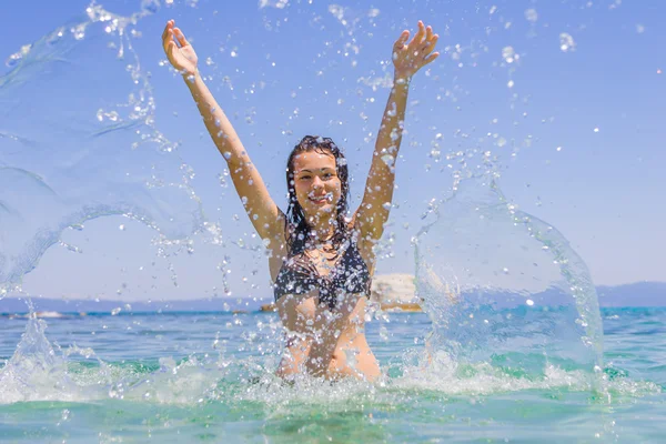 Junge Frau im Meer beim Wasserspritzen — Stockfoto