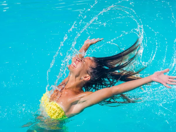 Young tanned girl throwing wet hair back in swimming pool — Stock Photo, Image