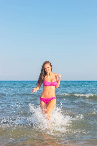 Jovem mulher de biquíni na praia salpicando água — Fotografia de Stock