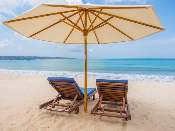 Расслабляющие кресла с зонтиком на белом песчаном пляже — стоковое фото