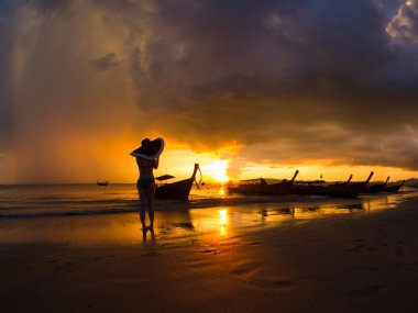 Woman on the beach at sunset on Ao Nanag beach in Krabi  clipart