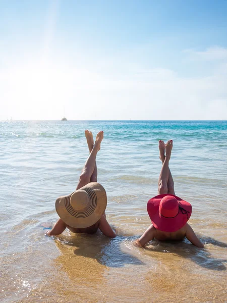 两位年轻女子在沙滩上休息的夏天帽子 — 图库照片