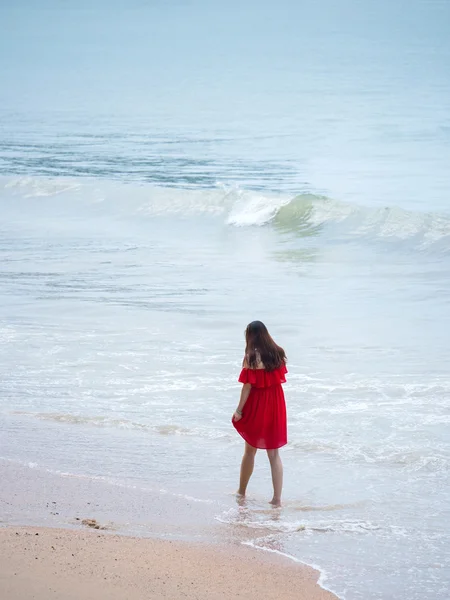 Femme en robe rouge marchant sur la plage — Photo