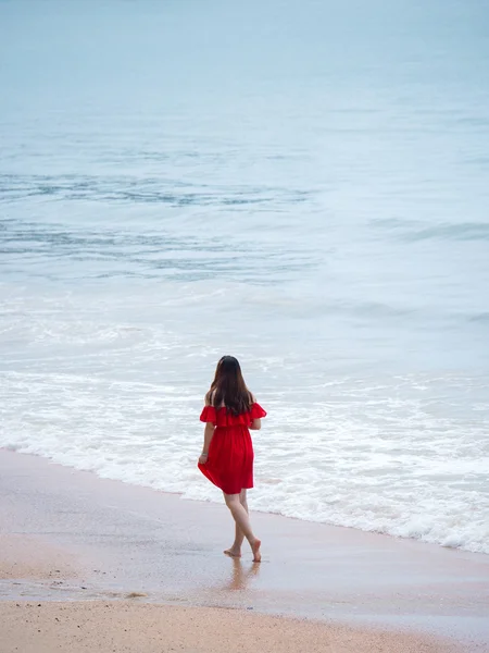빨간 옷을 입고 해변을 걷고 있는 여자 — 스톡 사진