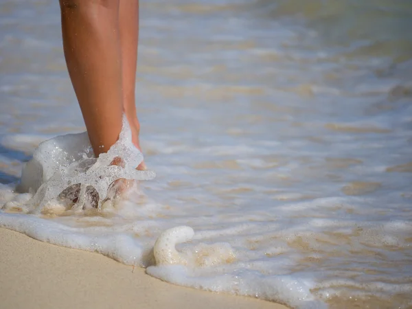 Primer plano de piernas de mujer en la orilla del mar — Foto de Stock