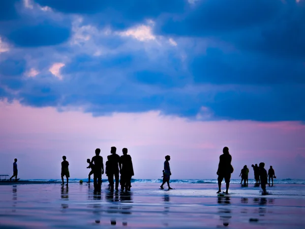 Silhuetas de pessoas ao pôr do sol na praia de Kuta Bali I — Fotografia de Stock