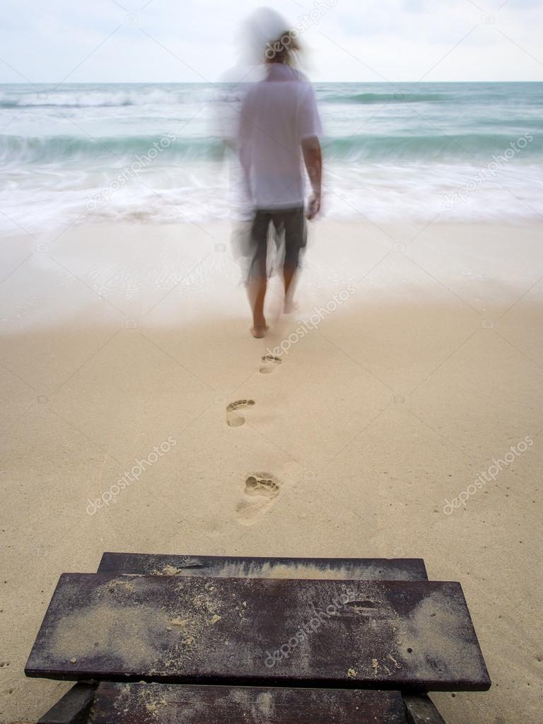 Back view of a man walking on the sand of a beach