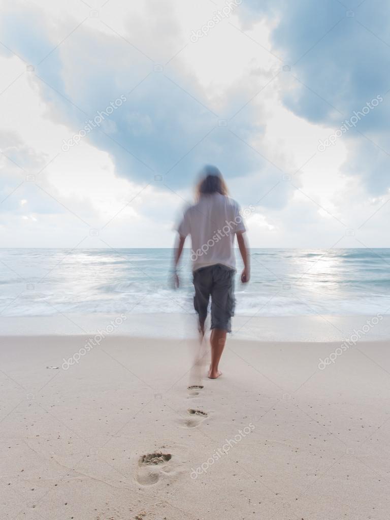 Back view of a man walking on the sand of a beach