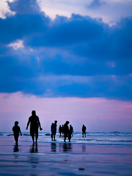 Silhuetter av folk vid solnedgången på stranden i Kuta Bali jag — Stockfoto