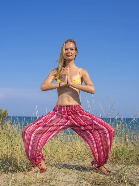 Kvinnan sträcker sig under yoga på stranden — Stockfoto