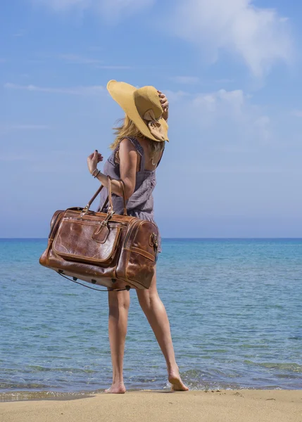 Frau mit Lederreisetasche am Strand — Stockfoto