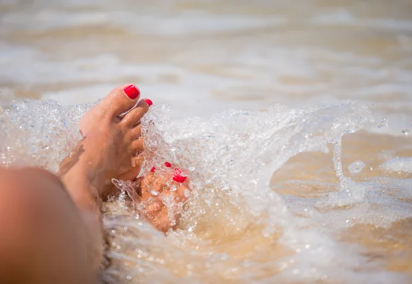 Gebruinde voeten met pedicure en de turquoise zee — Stockfoto