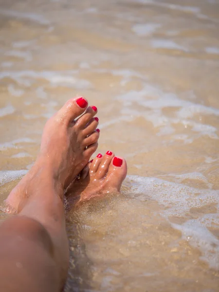 Tanned feet with pedicure  and the turquoise sea — Stock Photo, Image