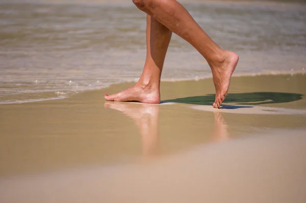 Stänk på kvinnliga ben på stranden — Stockfoto