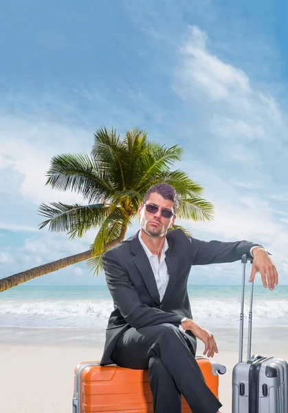 Mann im Anzug sitzt auf seinem Gepäck am Strand — Stockfoto