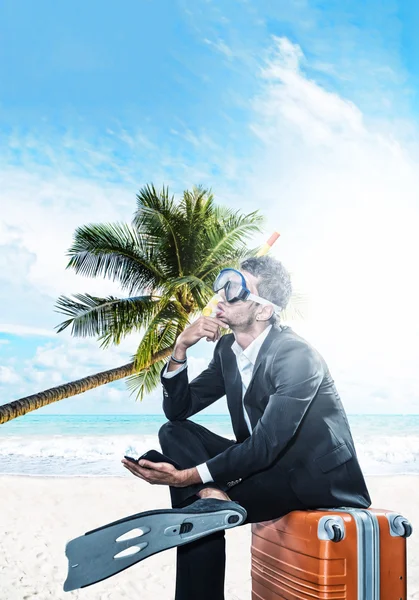 Man i kostym som sitter på en resväska på stranden — Stockfoto