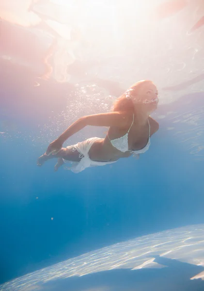 Genç bir kadın su altında yüzüyor. — Stok fotoğraf