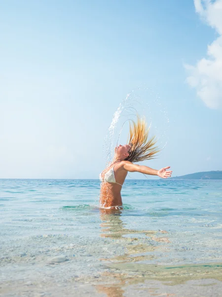 Mujer rubia en el agua agitando el pelo — Foto de Stock