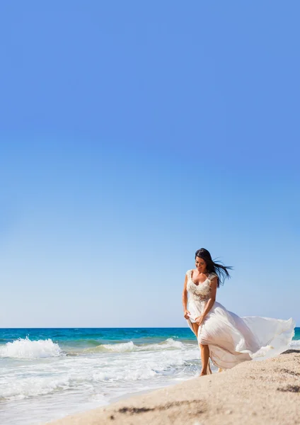 Mooie jonge bruid wandelen op het strand — Stockfoto