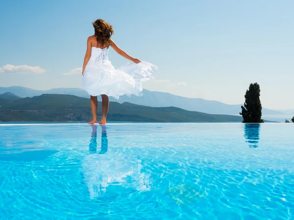 Novia de pie en el borde de la piscina infinita — Foto de Stock