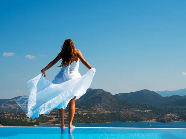 Novia de pie en el borde de la piscina infinita — Foto de Stock