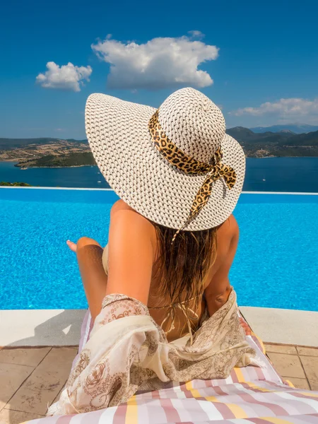 Mujer sosteniendo un cóctel fresco relajándose junto a la natación infinita — Foto de Stock