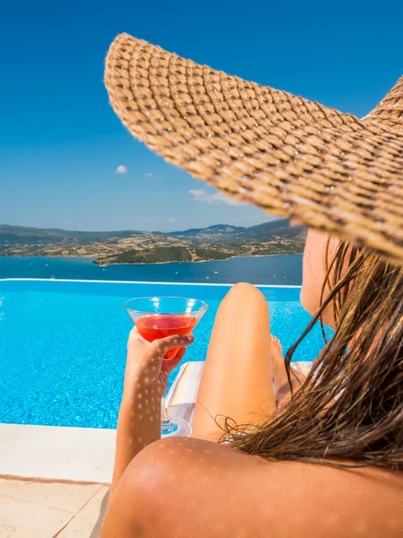 Donna che regge un cocktail fresco e rilassante vicino alla piscina a sfioro — Foto Stock