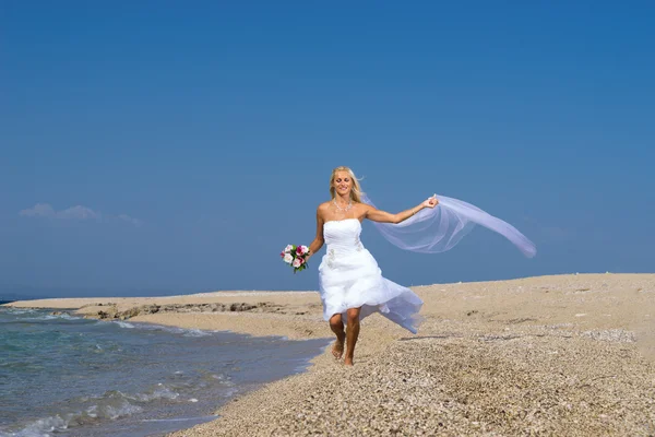 Young bride in wedding drees having fun on the beach — Stockfoto