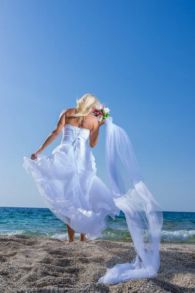 Young bride in wedding drees having fun on the beach — Stok fotoğraf