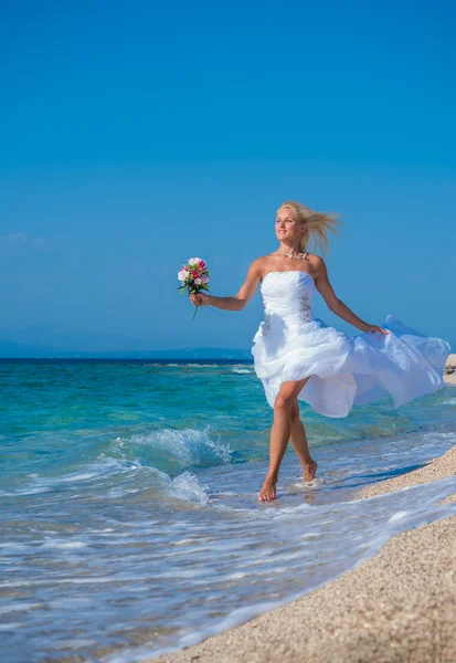 Young bride in wedding drees having fun on the beach — Zdjęcie stockowe