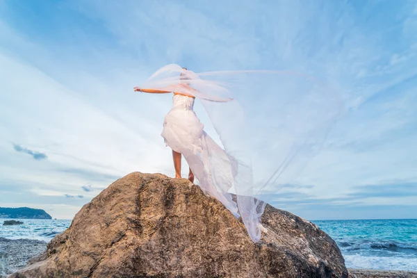 Jeune mariée au bord de la mer au coucher du soleil — Photo