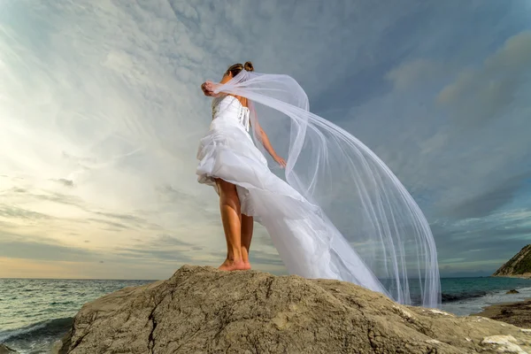 Jeune mariée au bord de la mer au coucher du soleil — Photo