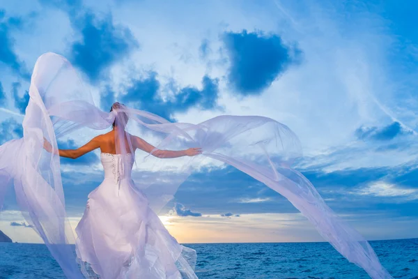 Jeune mariée au bord de la mer au coucher du soleil — Photo