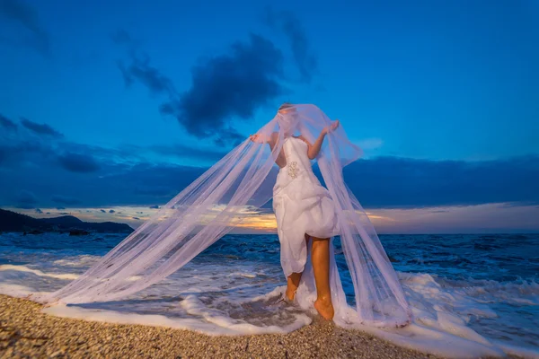 Jeune mariée au bord de la mer au coucher du soleil — Photo