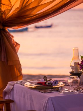 Gün batımında sahilde romantik bir akşam yemeği ayar