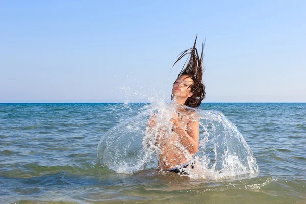 Krásná mladá žena v bikinách na pláži šplouchání — Stock fotografie