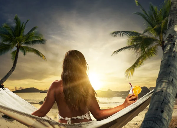 Junge Dame entspannt sich in der Hängematte am Strand bei Sonnenuntergang — Stockfoto