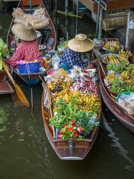 Traders selling vegetables and fruits by sailing a boat in a fl