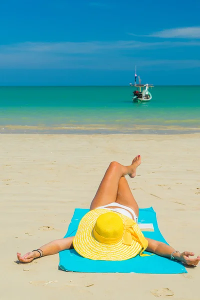 Mulher de biquíni amarelo deitada na praia tropical — Fotografia de Stock