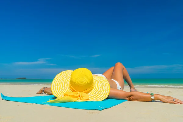 Frau im gelben Bikini liegt am tropischen Strand — Stockfoto